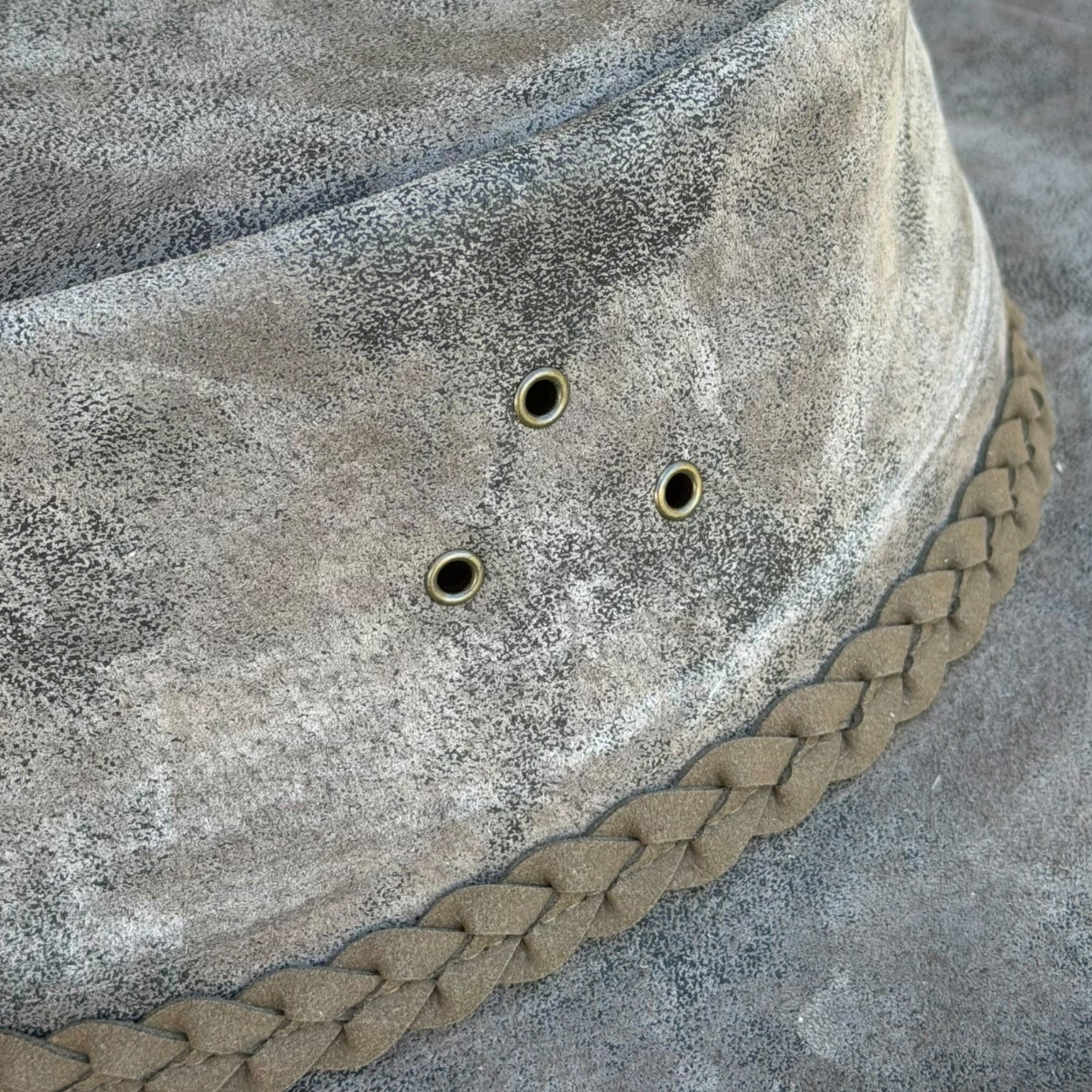 Dettaglio occhielli metallici e intreccio del cappello in pelle