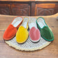 Scarpe friulane disposte a raggiera nei colori arancione, giallo, rosa e verde smeraldo